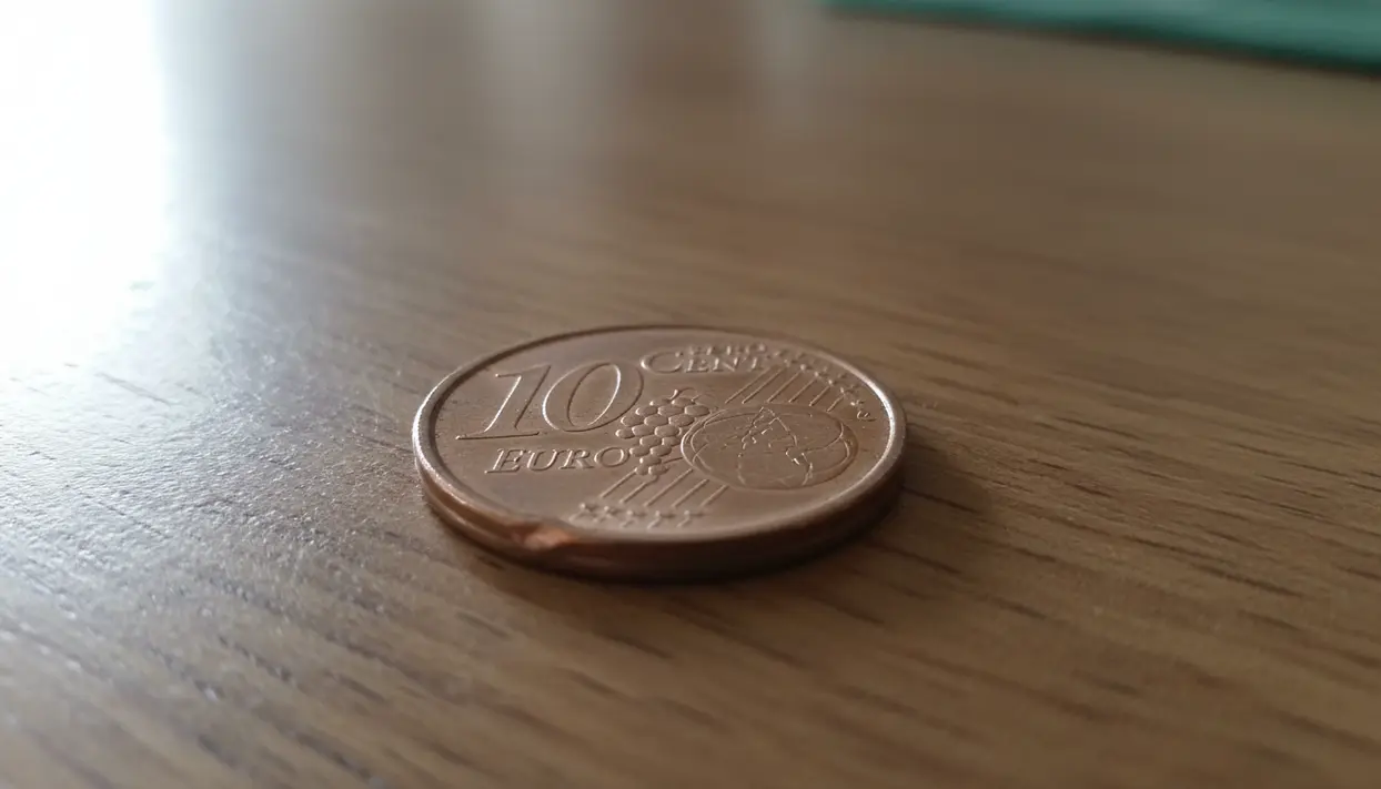 Moneta da 10 centesimi euro appoggiata su un tavolo di legno, in primo piano