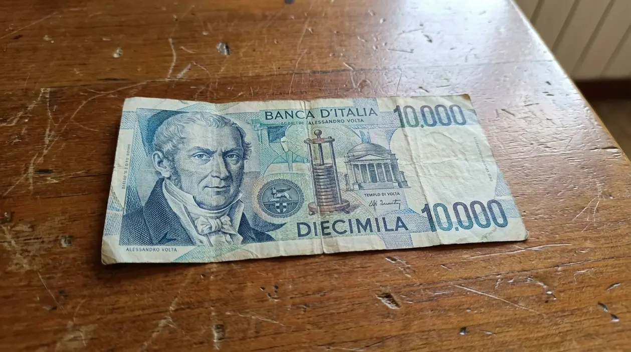 Banconota da 10.000 lire con Alessandro Volta appoggiata su un tavolo di legno, usurata e con pieghe visibili