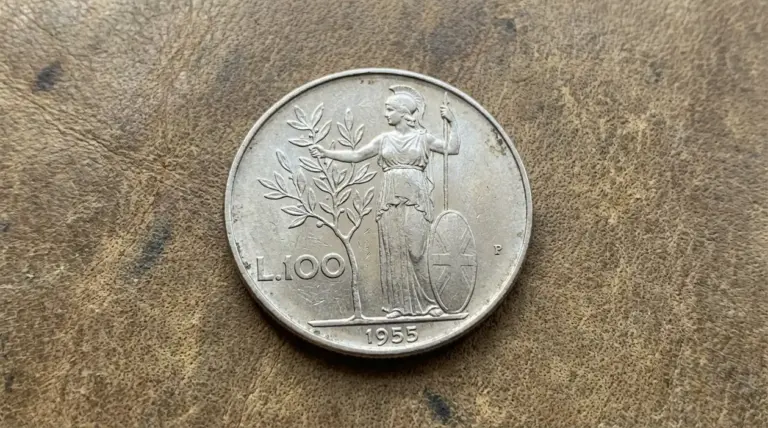 Moneta da 100 lire Minerva del 1955, con figura di Minerva e albero d’ulivo, fotografata su superficie marrone