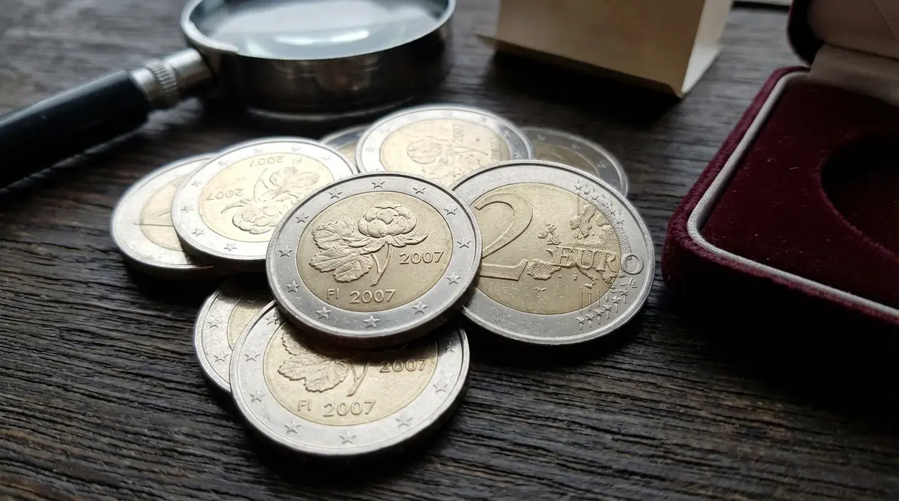 Monete da 2 euro Finlandia 2007 commemorative su tavolo in legno, con lente d’ingrandimento e astuccio