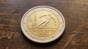 Moneta commemorativa da 2 euro Torino 2006 con sciatore e simboli olimpici su superficie in legno