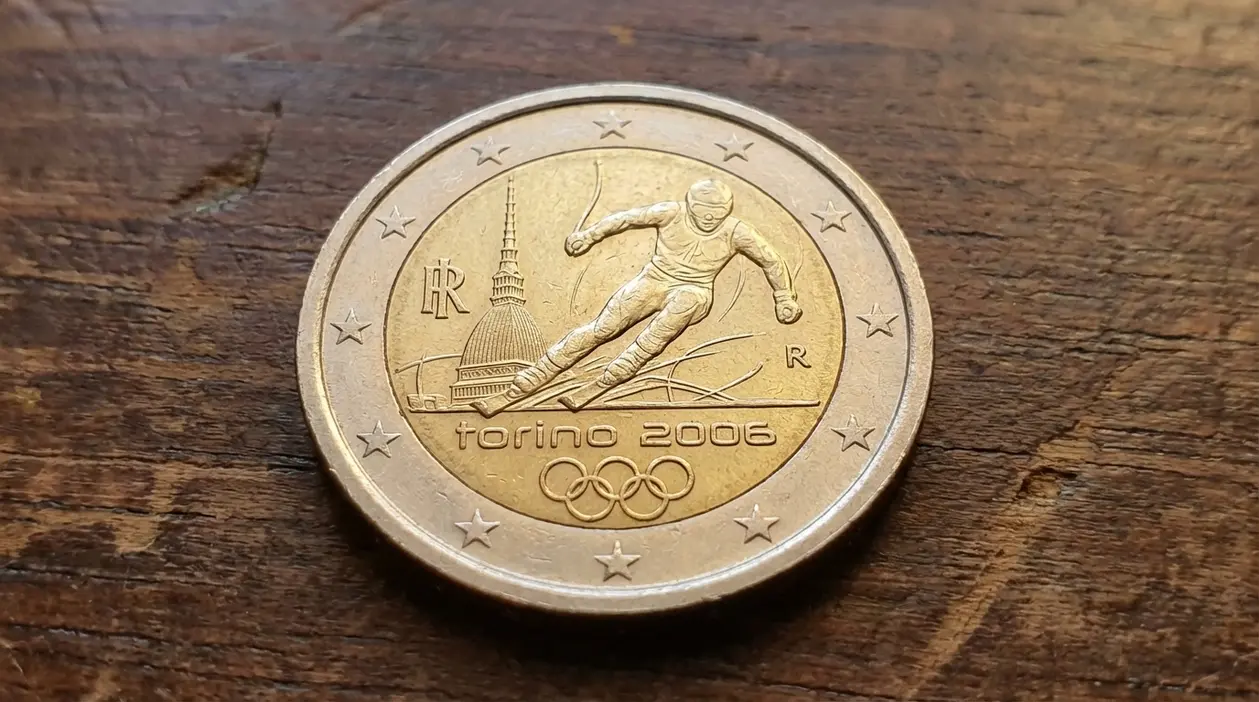 Moneta commemorativa da 2 euro Torino 2006 con sciatore e simboli olimpici su superficie in legno