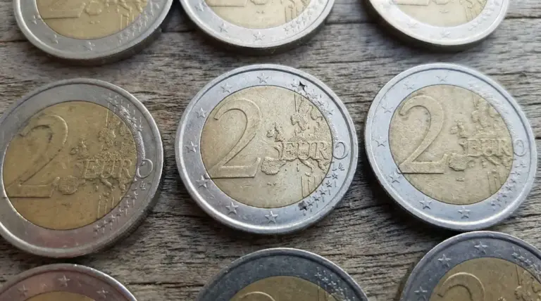 Monete da 2 euro su superficie in legno, con dettagli delle stelle sul bordo visibili in primo piano