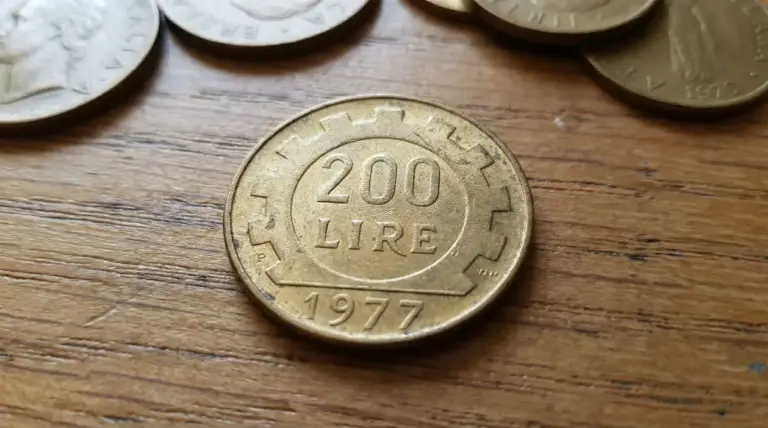 Moneta da 200 lire del 1977 su superficie in legno con altre monete sullo sfondo