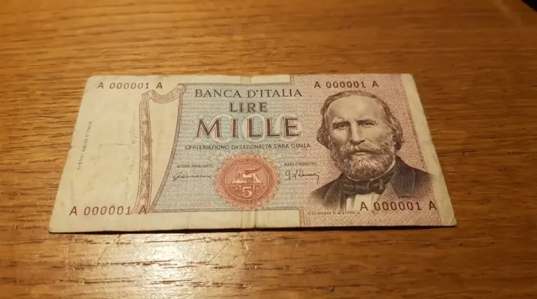 Banconota da 1.000 lire con ritratto di Garibaldi e numero di serie basso, appoggiata su un tavolo in legno