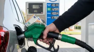 Rifornimento di carburante a un’auto con pistola verde, con banconote in euro e prezzi esposti sullo sfondo