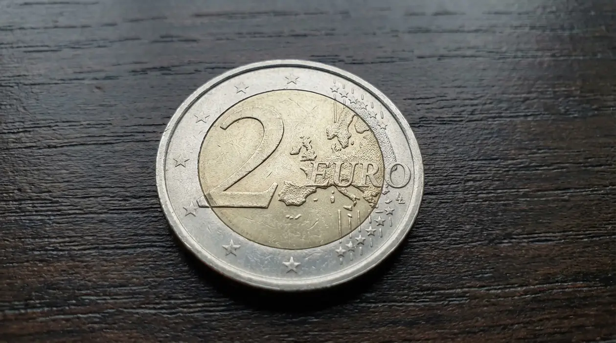 Moneta da 2 euro su superficie in legno, dettaglio del lato comune con mappa dell’Europa e stelle