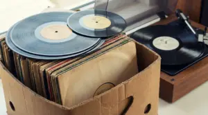Scatola di cartone con dischi in vinile e giradischi sullo sfondo, per valutare una collezione di vinili rari