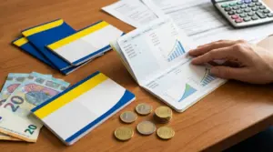 Libretto di risparmio aperto con grafici di crescita, euro in banconote e monete su una scrivania