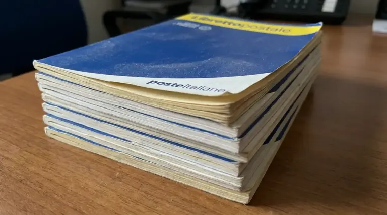 Pila di libretti postali cartacei su una scrivania, simbolo dei libretti postali dormienti da riscuotere