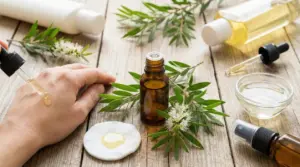Applicazione di olio di tea tree su una mano con flacone e foglie sullo sfondo