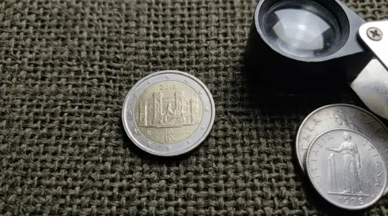 Moneta da 2 euro italiana del 2018 su tessuto, accanto a lente d’ingrandimento per controllare un microerrore