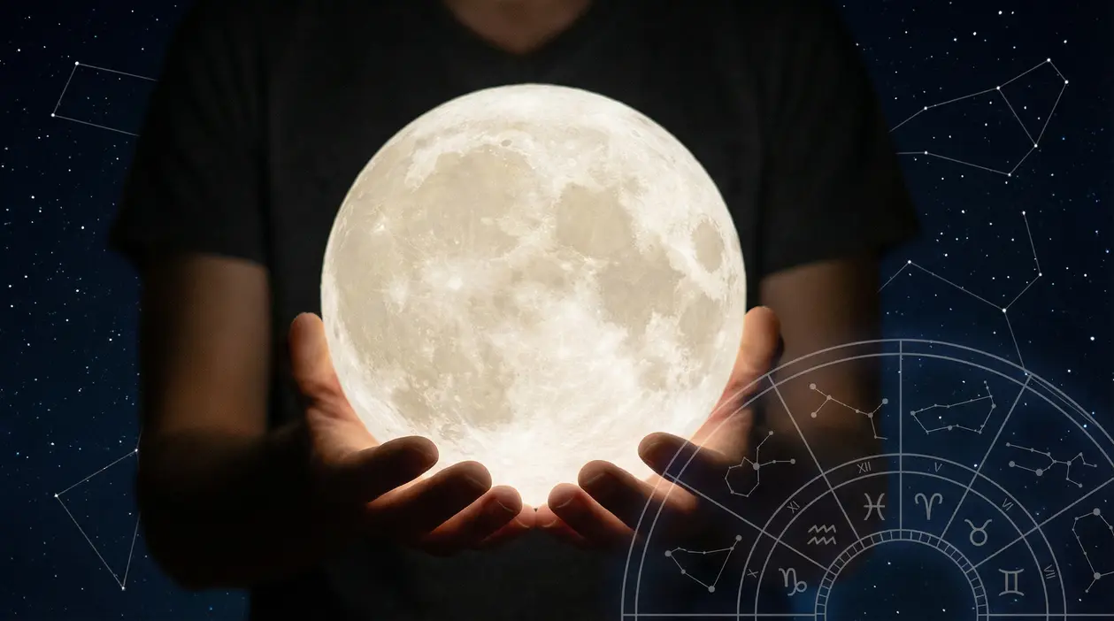 Persona che tiene una luna luminosa con costellazioni zodiacali sullo sfondo