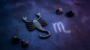 Simbolo dello Scorpione con piccole pietre nere su sfondo blu violaceo