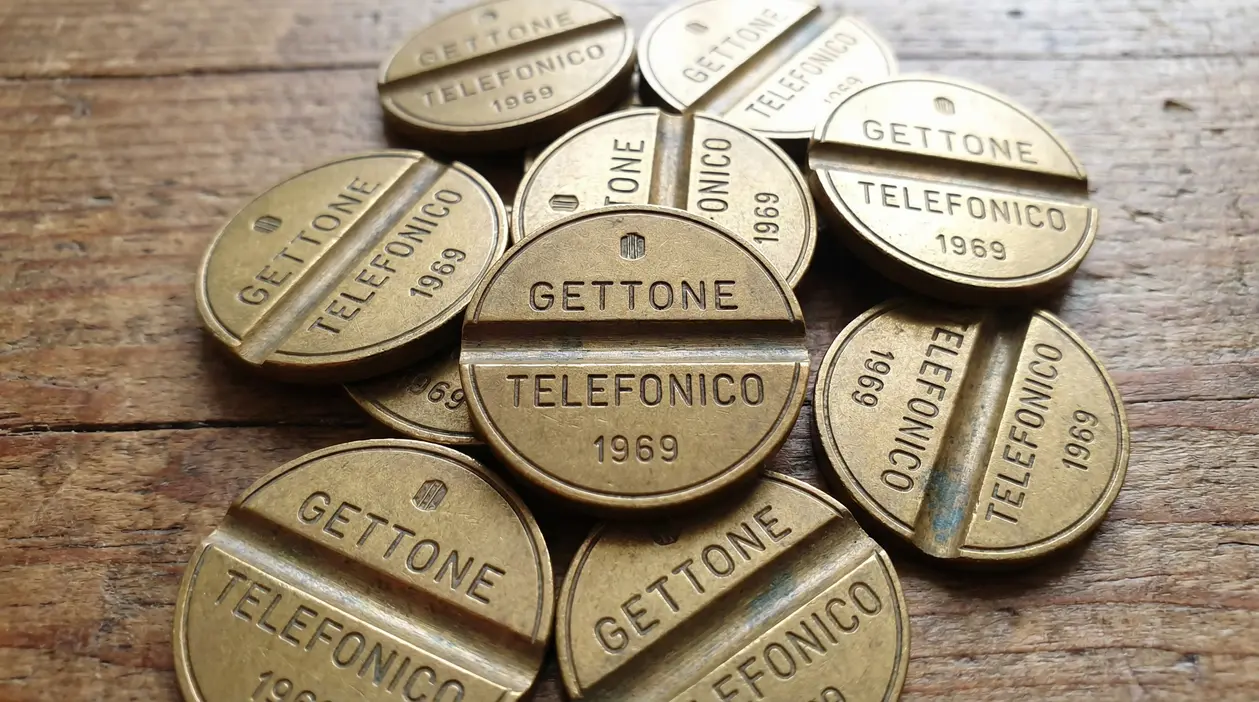 Gettoni telefonici italiani del 1969 disposti su una superficie in legno