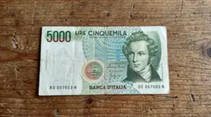 Vecchia banconota da 5.000 lire italiane appoggiata su un tavolo di legno