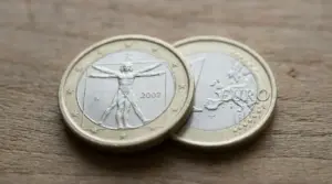 Due monete da 1 euro su un tavolo, una con il disegno dell’Uomo Vitruviano e l’anno 2002